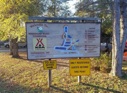Sign for Meridian East Toomsuba KOA Campground, with directions and rules for registered guests.