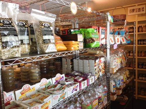 A well-stocked grocery shelf featuring various packaged foods, including pasta, snacks, and jars of spreads.