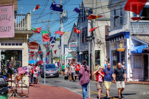 A bustling street scene with colorful flags, shops, and people walking, creating a lively atmosphere.