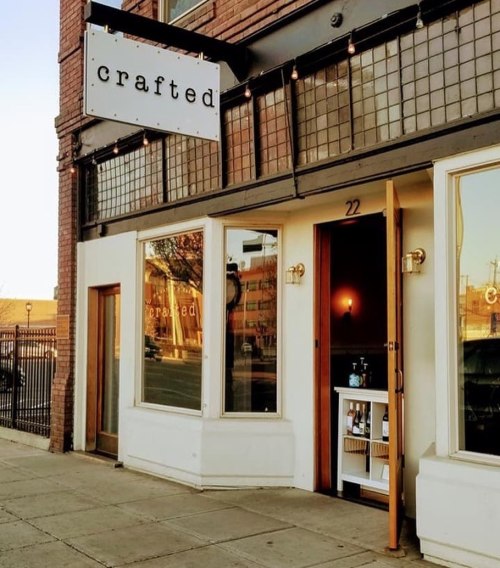 Exterior of a shop named "crafted," featuring large windows and a welcoming entrance on a sunny day.