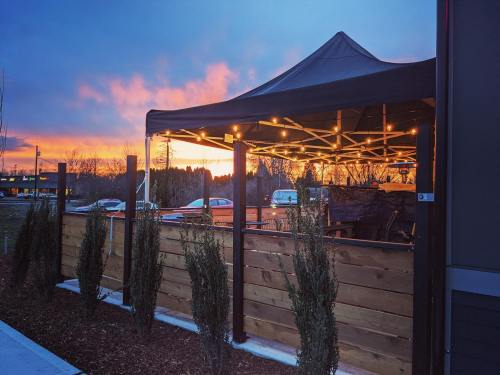 A cozy outdoor seating area with a tent, string lights, and a colorful sunset in the background.