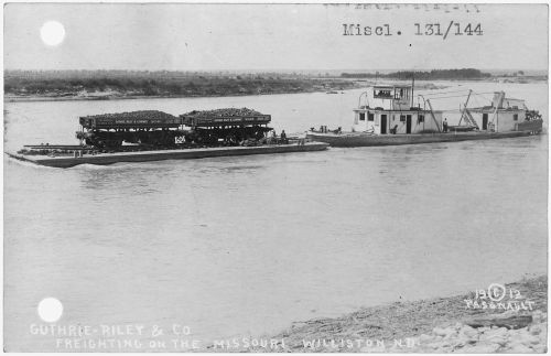 Black and white photo of a barge and tugboat on the Missouri River, labeled "Guthrie-Riley & Co. Freighting."