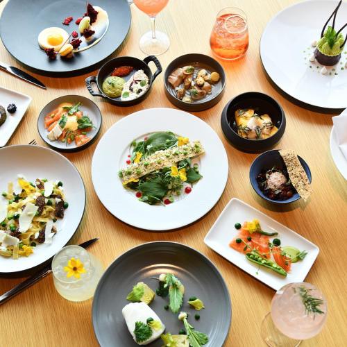 A beautifully arranged table with various gourmet dishes, including salads, seafood, desserts, and colorful drinks.