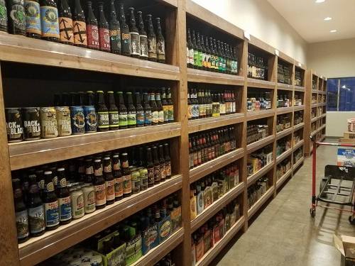 A well-stocked aisle of shelves filled with various beer bottles and cans in a store.
