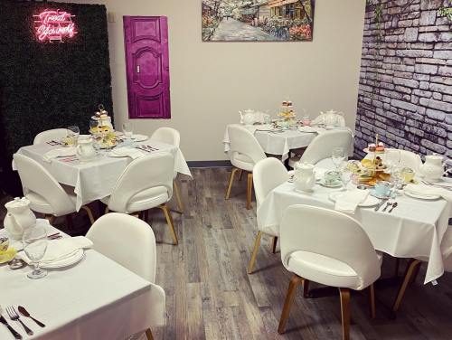 A cozy restaurant with white tables, elegant tea sets, and a vibrant pink door decor.