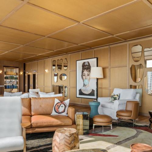 A stylish living room featuring leather sofas, a large artwork, and unique decor elements in warm tones.
