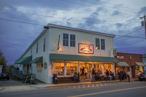 A charming country store with a bright sign, people sitting outside, and a cloudy evening sky.