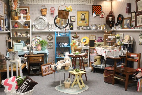 A cozy vintage shop filled with various antiques, decor items, and furniture arranged on shelves and tables.