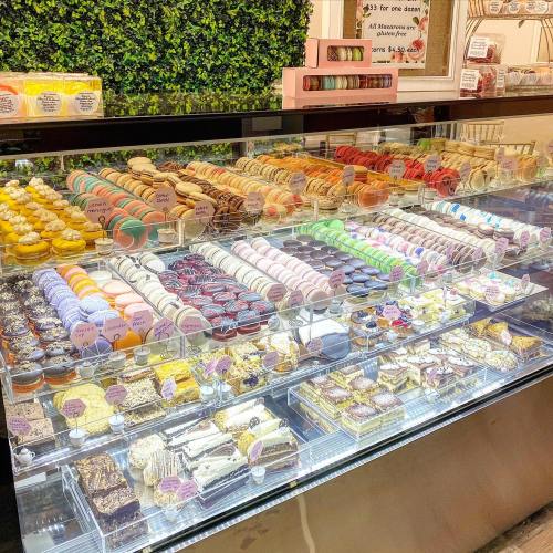 A display case filled with a variety of colorful pastries, including macarons, cakes, and desserts.