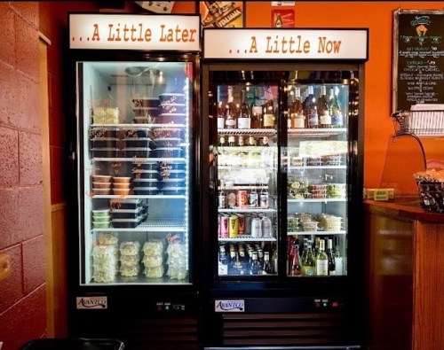 Two glass-front refrigerators labeled "A Little Later" and "A Little Now," filled with food and beverages.