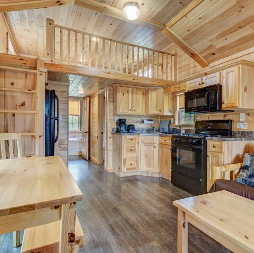 Cozy wooden cabin interior featuring a kitchen, dining area, and loft with natural light and rustic decor.