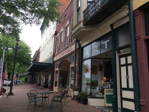 Charming street view of shops with outdoor seating, featuring an art gallery and historic buildings.