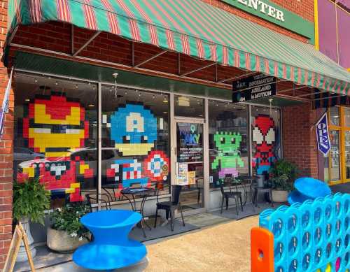 Colorful pixel art of superheroes on a storefront window, featuring Iron Man, Captain America, Hulk, and Spider-Man.