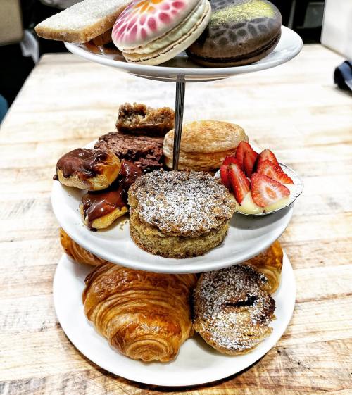 A tiered dessert stand featuring various pastries, including macarons, croissants, and fruit-topped treats.