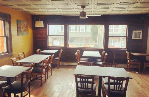 Cozy restaurant interior with wooden tables and chairs, large windows, and a warm, inviting atmosphere.