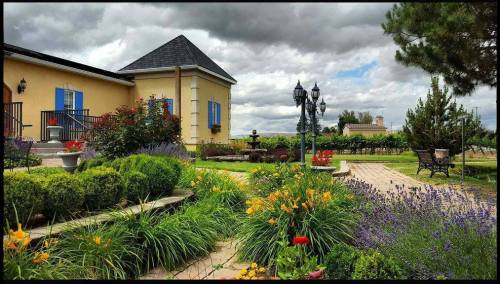A picturesque garden with colorful flowers, a stone pathway, and a charming house under a cloudy sky.