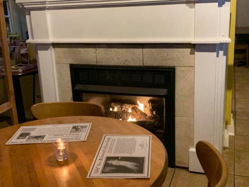 A cozy restaurant scene featuring a fireplace and a wooden table with a candle and menus.