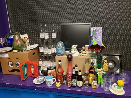 A colorful display of various items, including bottles, glasses, and decorative objects, arranged on boxes and a table.