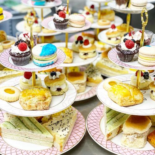 A tiered display of assorted pastries, including cupcakes, macarons, scones, and mini cakes, beautifully arranged on plates.
