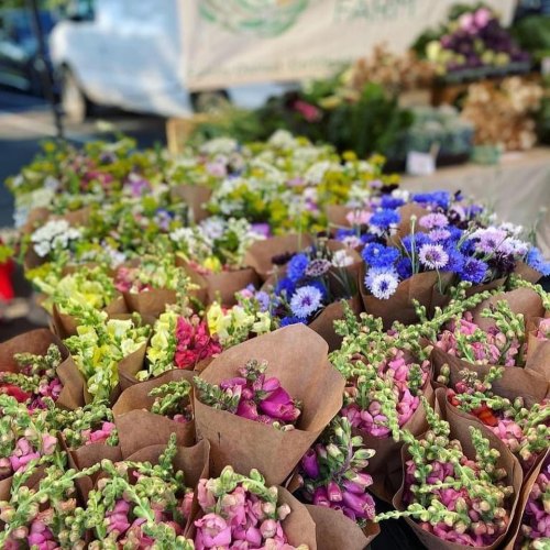 A vibrant display of assorted flower bouquets in brown paper wraps at a market stall.