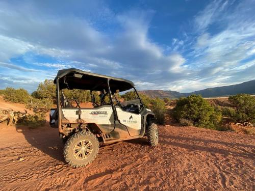 A side-by-side off-road vehicle parked on a rocky terrain with a scenic view of hills and blue sky in the background.