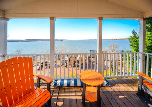 A cozy porch with orange chairs and a table, overlooking a serene lake and clear blue sky.