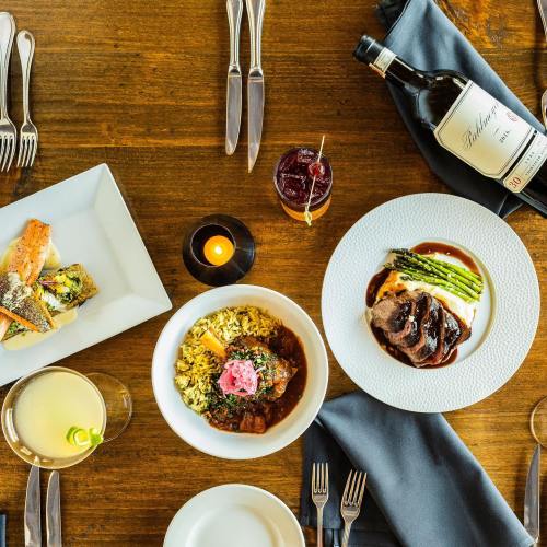 A beautifully arranged table with gourmet dishes, drinks, and elegant cutlery, featuring a main course and side dishes.