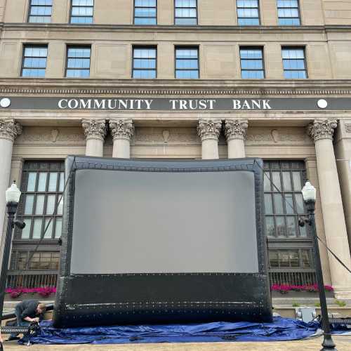 An inflatable movie screen set up in front of the Community Trust Bank building.