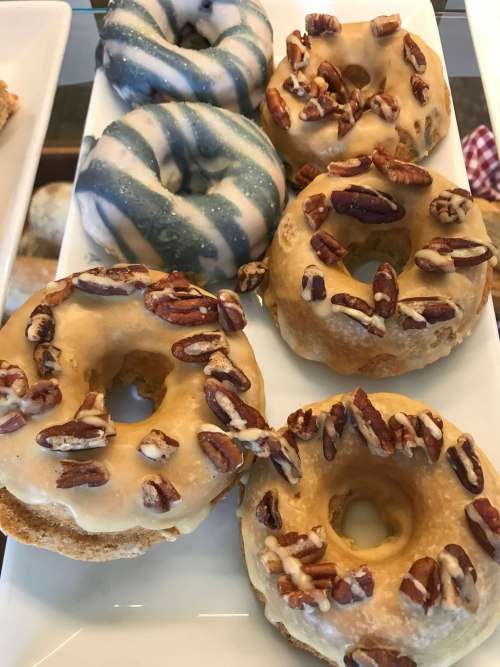 A platter of assorted donuts: two with blue swirls and three topped with pecans and a glaze.