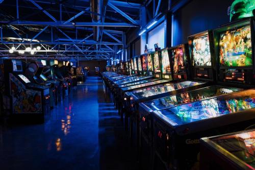 A dimly lit arcade featuring rows of colorful pinball machines and classic arcade games.