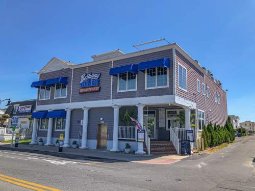 A coastal restaurant with blue awnings and a sign reading "Bethany Blues" on a sunny day.