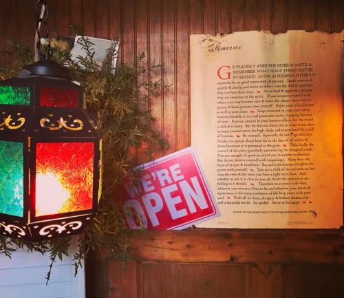 A colorful lantern and an "Open" sign next to a framed text on a wooden wall, creating a warm, inviting atmosphere.