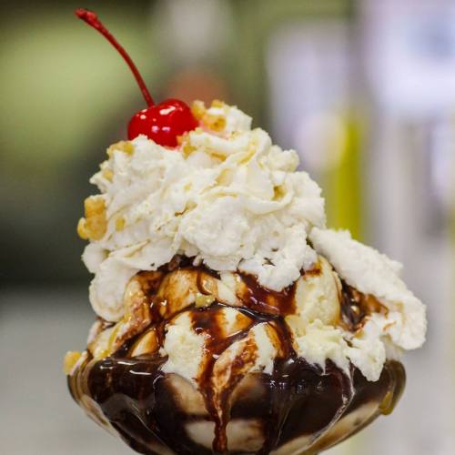 A delicious ice cream sundae topped with whipped cream, chocolate sauce, and a cherry.