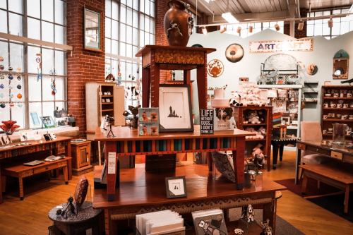 A cozy craft store interior featuring wooden furniture, art displays, and colorful decor items.