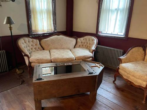 A cozy room featuring a vintage sofa, an ornate chair, and a wooden coffee table with a glass top.