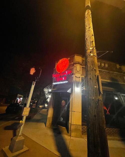 A dimly lit street scene featuring "The Haunted House" restaurant sign at night, with a traffic signal nearby.