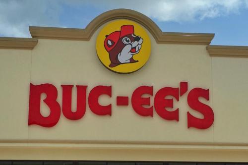 Sign for Buc-ee's featuring a beaver mascot and bold red lettering against a light background.