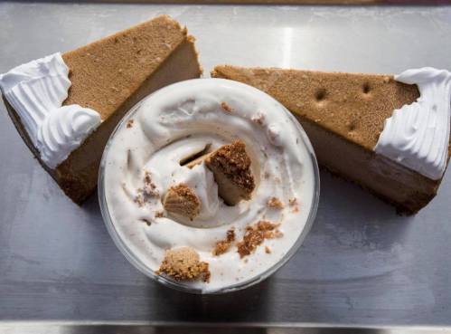 A bowl of creamy dessert topped with crumbled cake, flanked by two slices of cake with whipped cream.