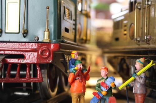 Close-up of miniature figures interacting near model trains, showcasing detailed craftsmanship and vibrant colors.