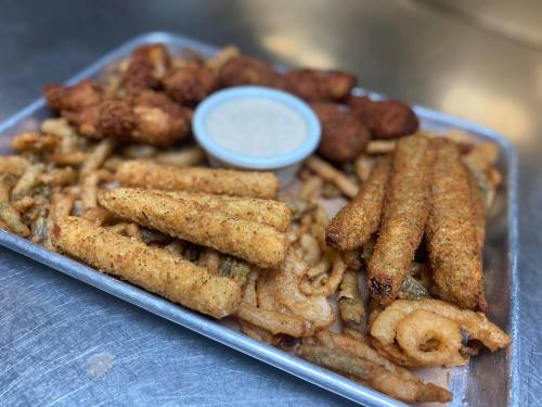 A metal tray filled with various fried foods, including fish, chicken, and a small bowl of dipping sauce.
