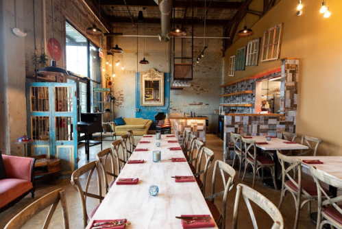 A cozy restaurant interior with wooden tables, colorful decor, and warm lighting, featuring a mix of vintage and modern elements.