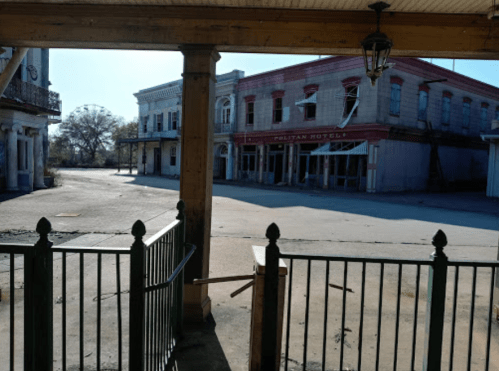 Abandoned street view featuring the old Politan Hotel and empty buildings under a clear blue sky.