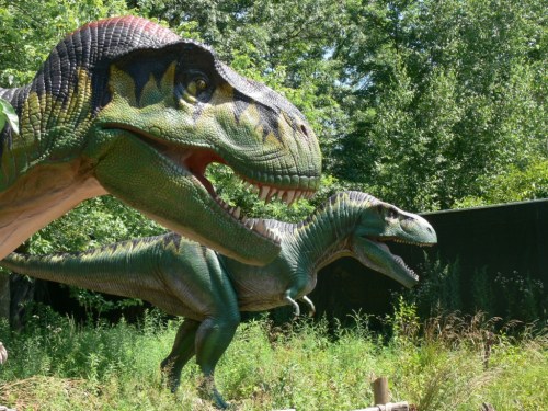 Two large dinosaur sculptures in a lush green setting, showcasing detailed textures and vibrant colors.