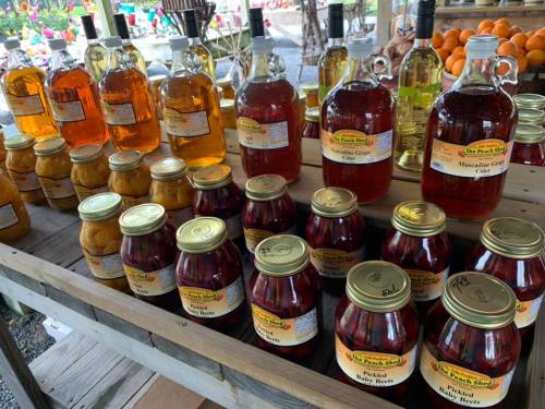 A display of various jars and bottles filled with colorful preserves and beverages at a market stand.