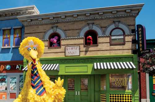 Big Bird stands in front of Hooper's Store, with two Muppet characters visible in the windows above.