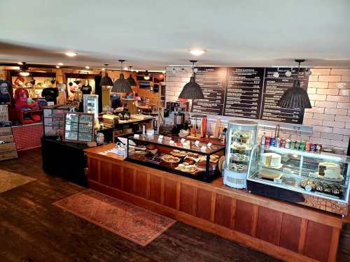 Cozy café interior with a wooden counter, display cases of pastries, and a menu board on the wall. Warm lighting.