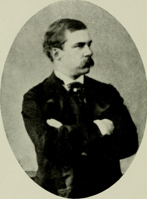 A vintage portrait of a man with a mustache, arms crossed, wearing a suit and bow tie, set against a plain background.