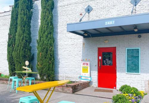 A bright red door with a menu board, surrounded by greenery and outdoor seating at a charming café.