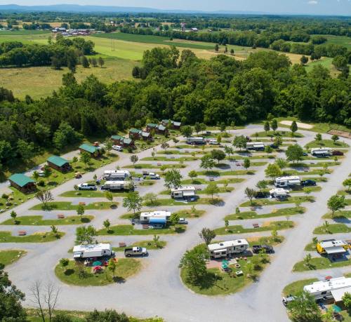 Aerial view of a campground with RVs and cabins surrounded by greenery and open fields.