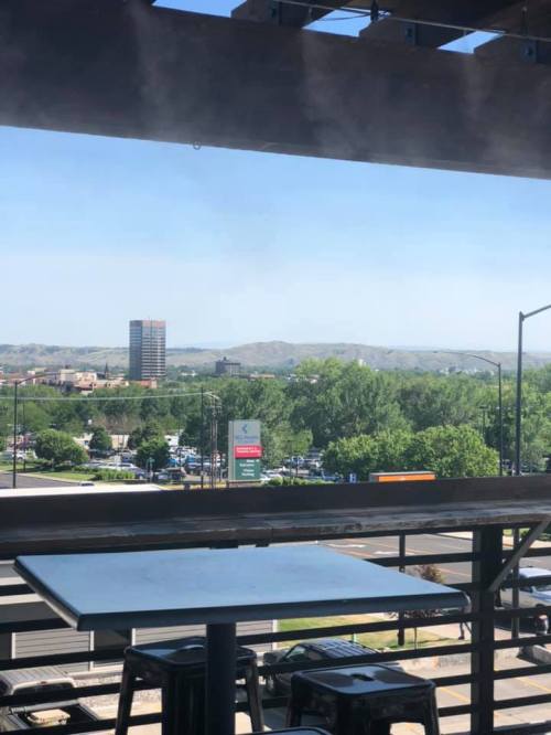 View from a balcony overlooking a cityscape with mountains in the background and a clear blue sky.
